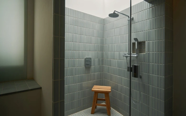 Zděný sprchový kout s dřevěnou lavičkou v moderním designu.