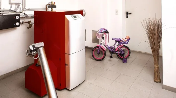 Červený kotel v místnosti s dětským bicyklem.