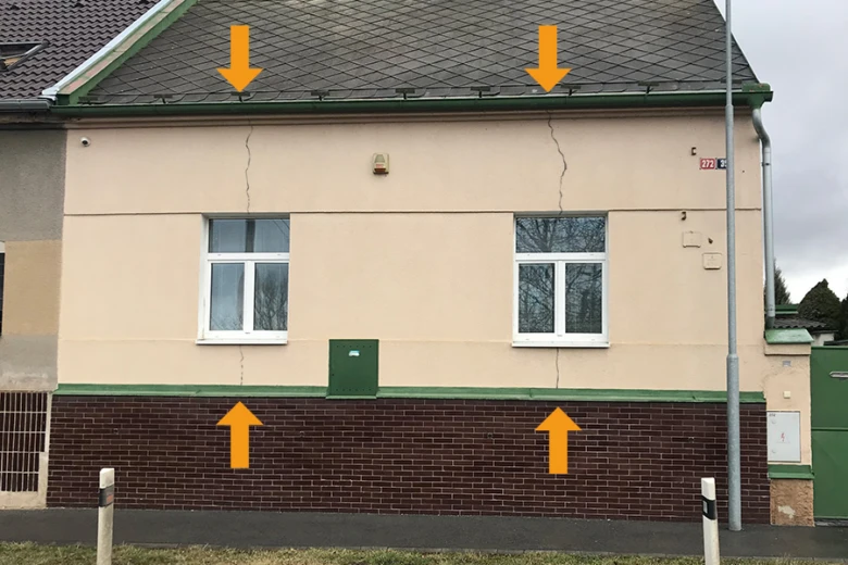 Trhliny ve zdivu domu od střechy až k základům.