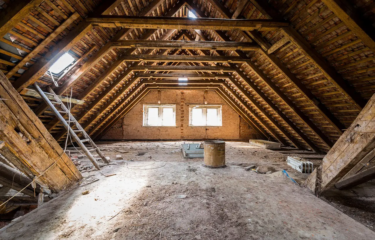 Neúplná půdní vestavba s dřevěnými trámy a okny.