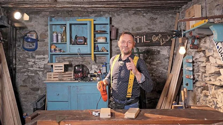 Dřevěný řemeslník s nástroji pro čepování trámů v dílně.