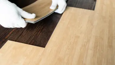 Montáž vinylové podlahy s rukavicemi na tmavém dřevěném povrchu.