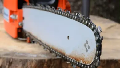 Detail motorové pily ukazující směr zubů řetězu na liště.