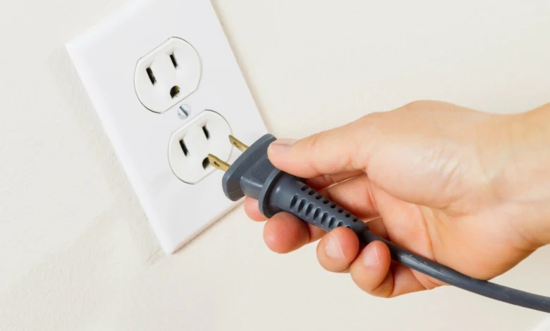 Ruka zapojuje šňůru do americké elektrické zásuvky.