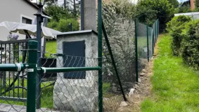 Zelený plot na svahu ukazuje stavbu plotu na nerovném terénu.