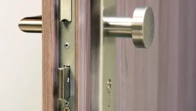 Detail zámku dveří s klikou a jazykem v rámu.