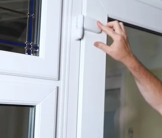 Ruka nastavuje regulovatelný závěs na plastovém okně.