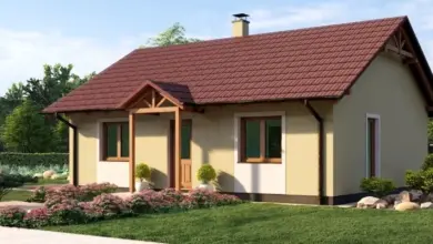 Moderní dům se sedlovou střechou a dřevěnými krovy na pozadí zelené zahrady.
