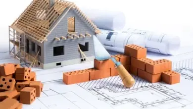 Model domu se cihlami a nářadím na pozadí plánů.