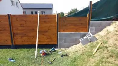 Stavba dřevěného plotu na svahu s nástroji a cihlami