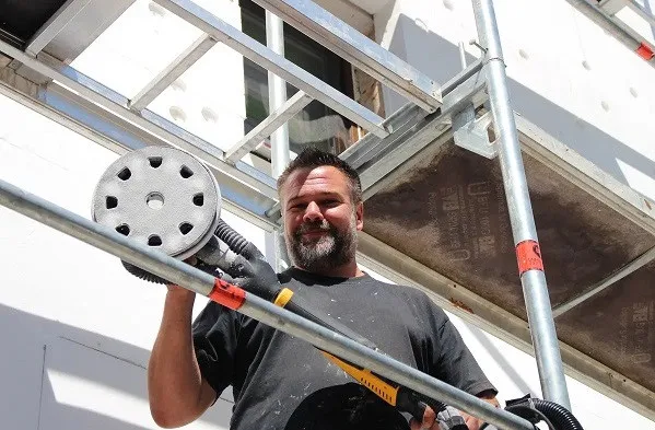 Man with sander on scaffolding