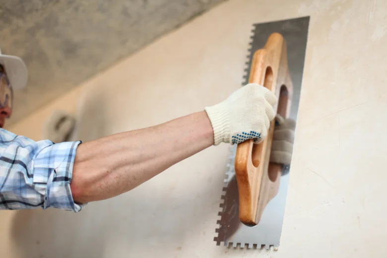 Pracovník hladí štuk na stěně před malováním.