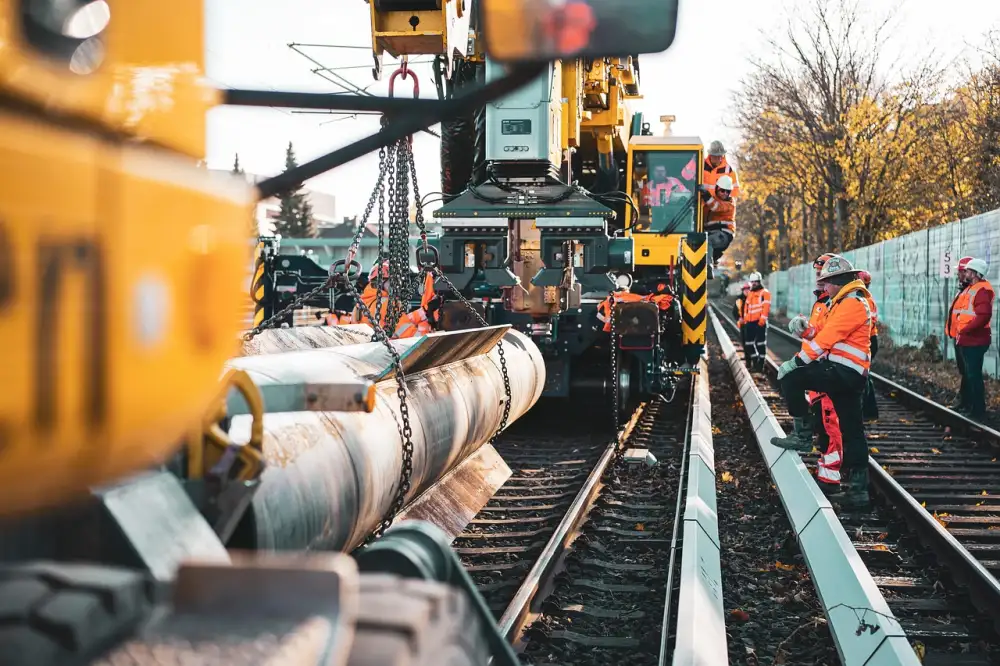 Stavební dělníci pracují na železniční trati s těžkou technikou.