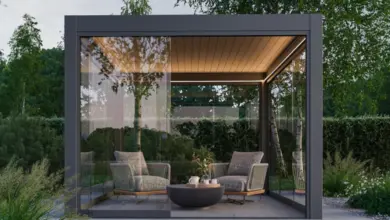 Moderní skleněná pergola s pohovkou v zahradním prostředí.