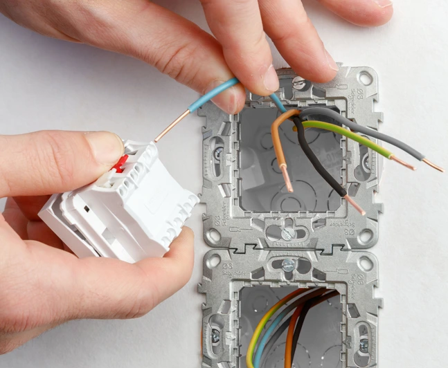 Ruční zapojení elektrického vypínače do stěnové krabice s vodiči.