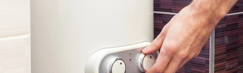 Ruka nastavuje teplotu na elektrokotle v koupelně.