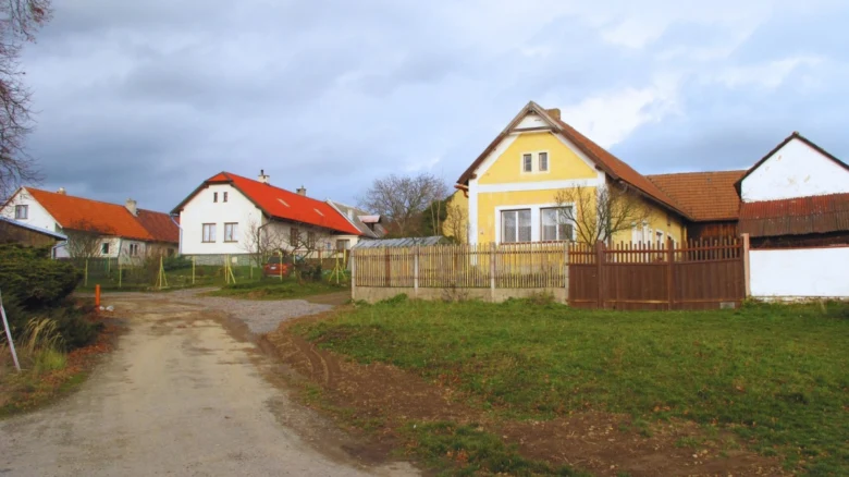 Venkovské domy s ploty na nezpevněné cestě v obci.