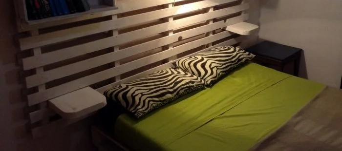Postel s hlavou z palety se zabudovanými policemi.
