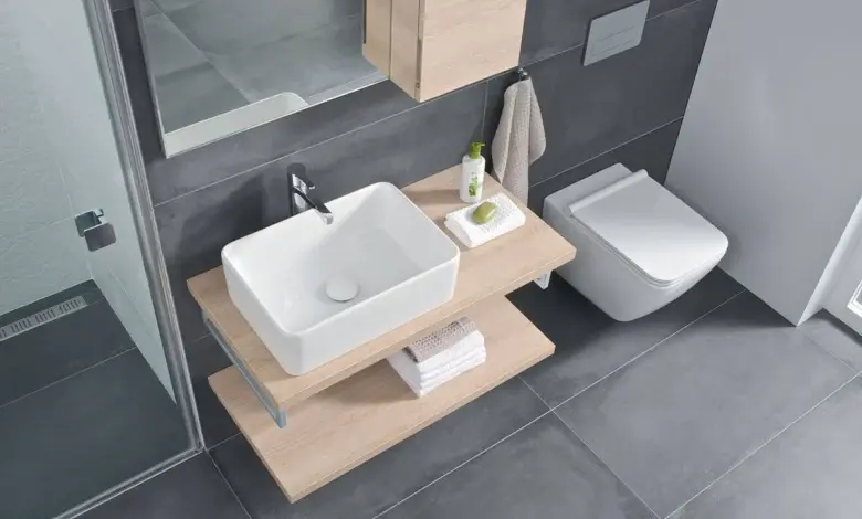 Moderní koupelna s umyvadlem a WC v tmavě šedých dlaždicích.