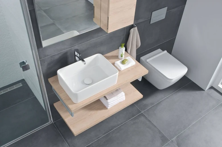 Moderní koupelna s umyvadlem a WC v tmavě šedých dlaždicích.