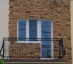 Fotografie fasády domu s cihlovou zdí a balkónem.