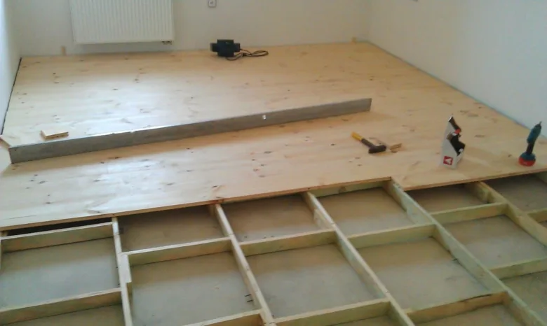 Instalace podlahového roštu s dřevěnými hranoly v průběhu stavby.