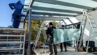 Muži montují skleněný panel do konstrukce zahradní pergoly.