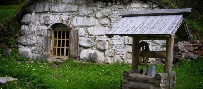 Hotový kamenný sklep v zemi s dřevěným oknem a čerpací stanicí.