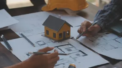 Architekti pracují s plány domu při schůzce o projektu.