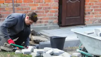 Muž ukládá dlažební kostky k zpevnění základu starého domu.
