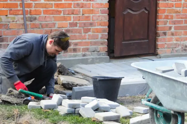 Muž ukládá dlažební kostky k zpevnění základu starého domu.