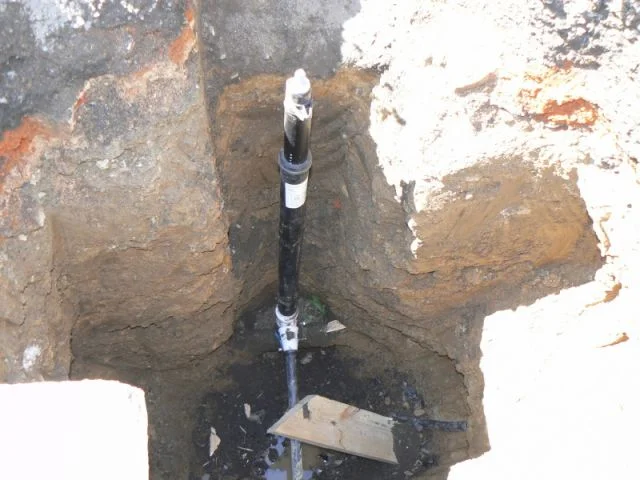 Černá vodovodní přípojka v zemi během samostatné instalace.