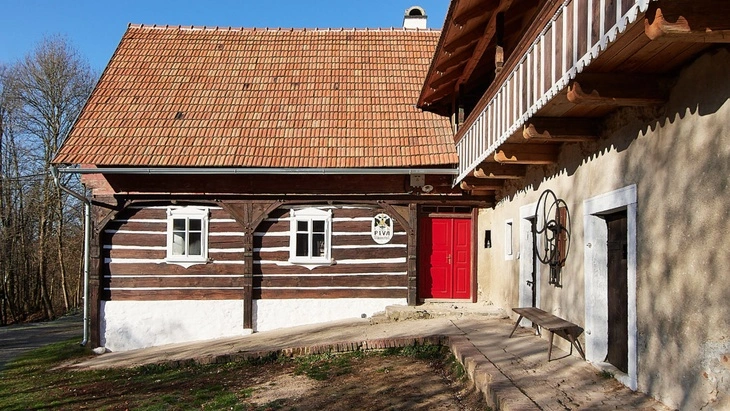 Tradiční hrázděný dům s dřevěným rámem a červenou střechou.