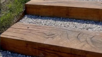 Dřevěné schody do svahu s bílým štěrkiem mezi trámy.