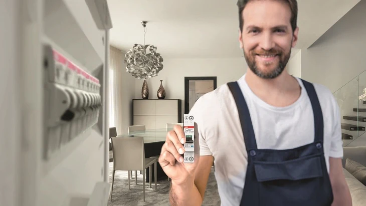 Elektrikář drží pojistkový spínač u rozvaděče v domácnosti.