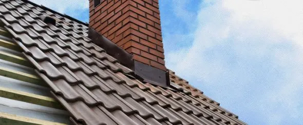 Kamínová komína z cihel na střeše s taškami.