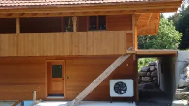 Venkovní jednotka tepelného čerpadla u dřevěného domu.
