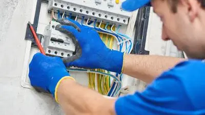 Elektrikář opravuje rozvaděč při přípojce elektřiny ze sloupu.