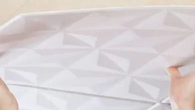 ruce instalují bílou stropní kazetu s geometrickým vzorem