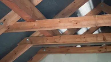 Dřevěné trámy střechy s viditelnými spoji a izolací pod nimi.