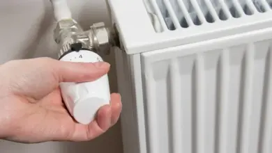 Ruka nastavuje průtok na bílém topném radiátoru.
