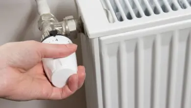 Ruka nastavuje termostatickou hlavici na radiátoru.