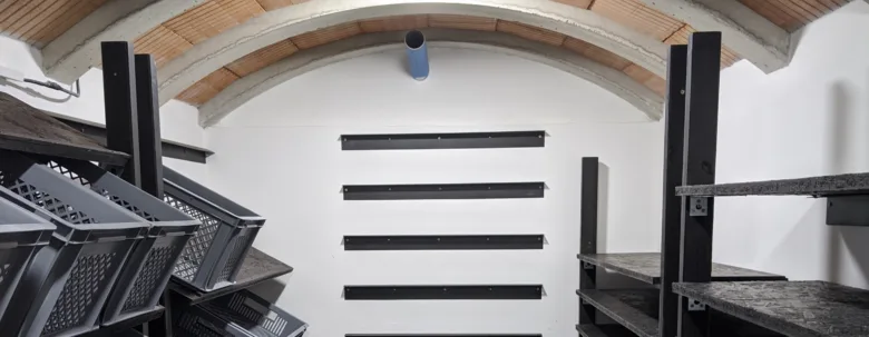 Vnitřek nadzemního sklepa s policemi a plastovými krabicemi pro uskladnění.