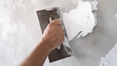 Ruční aplikace omítky na stěnu pomocí špachtle při opravě.