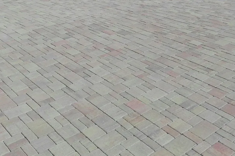 Pohled na dlažbu kolem domu z kostek v šedé barvě.