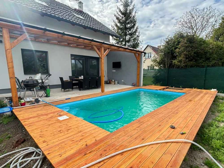 Dřevěné obložení kolem nadzemního bazénu u domu s terasou.