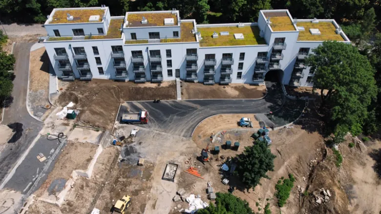 Nová budova bytového domu v průběhu výstavby na pozemku.