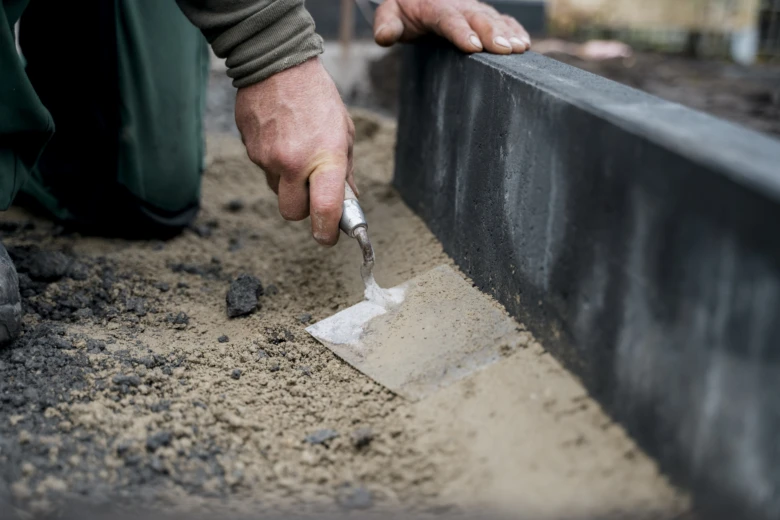 Ruční aplikace betonu na obrubník během stavby.