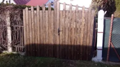 Dřevěná brána s plotem v zahradním prostředí.