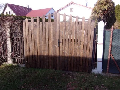 Dřevěná brána s plotem v zahradním prostředí.